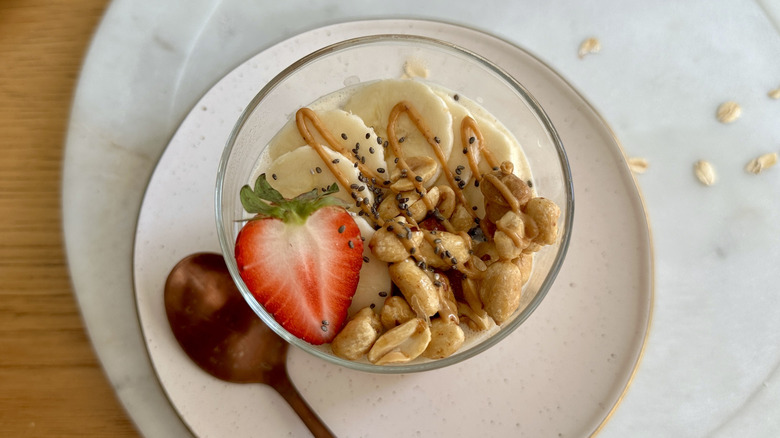 Overnight oats in jar topped with bananas, strawberry slice, peanuts, and peanut butter drizzle