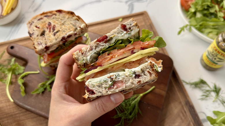 Hand holding smoked salmon sandwich