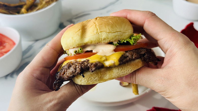 Hands holding cheese smash burger