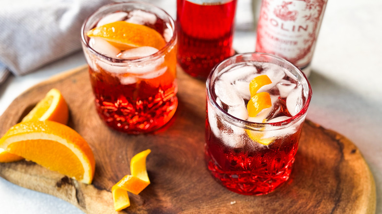 Classic Americano cocktails in rocks glasses with orange garnish on cutting board