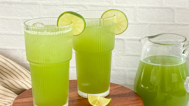 Glasses of cucumber agua fresca next to pitcher of agua fresca