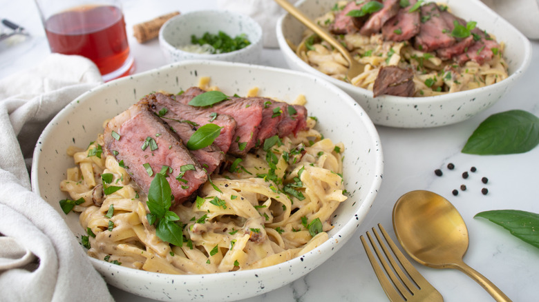 noodles with steak and herbs in white bowls