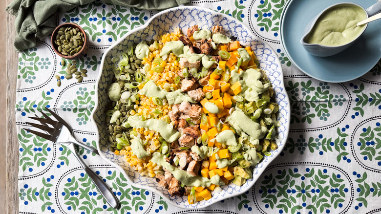 Chopped mango avocado chicken salad in serving bowl with avocado ranch dressing and pepitas