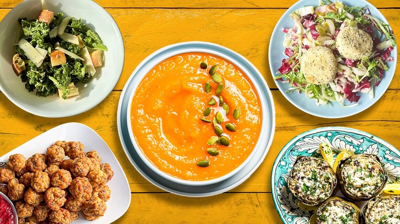 Bowl of butternut squash soup surrounded by various side dishes