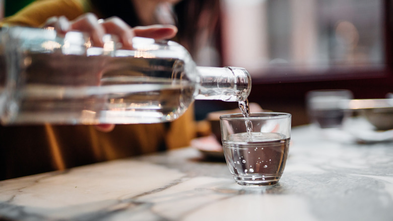 Close up shot of woman pouring water into glass