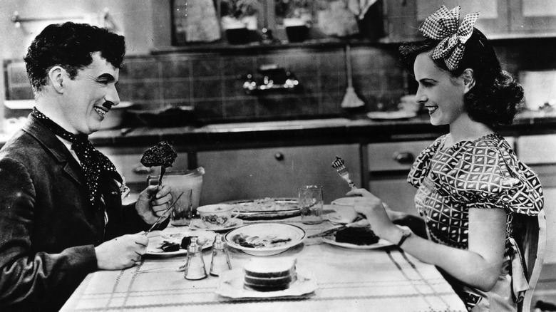 Black and white photo of Charlie Chaplin sharing dinner with a woman in a movie